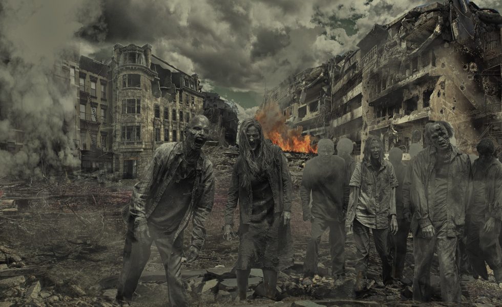 Grupo de zumbis no primeiro plano, ao fundo uma cidade destruída, fogo e fumaça numa imagem acinzentada.