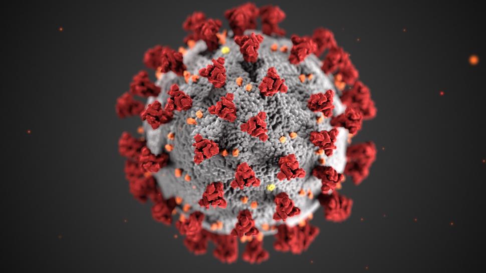 Ilustração do coronavírus feita pelo Centro de Controle e Prevenção de Doenças estadunidense. Esfera azul cinza clara com pequenos pontos laranjas e grandes vermelhos ao longo de sua superfície. O fundo é de um cinza escuro com alguns pontos luminosos laranjas.