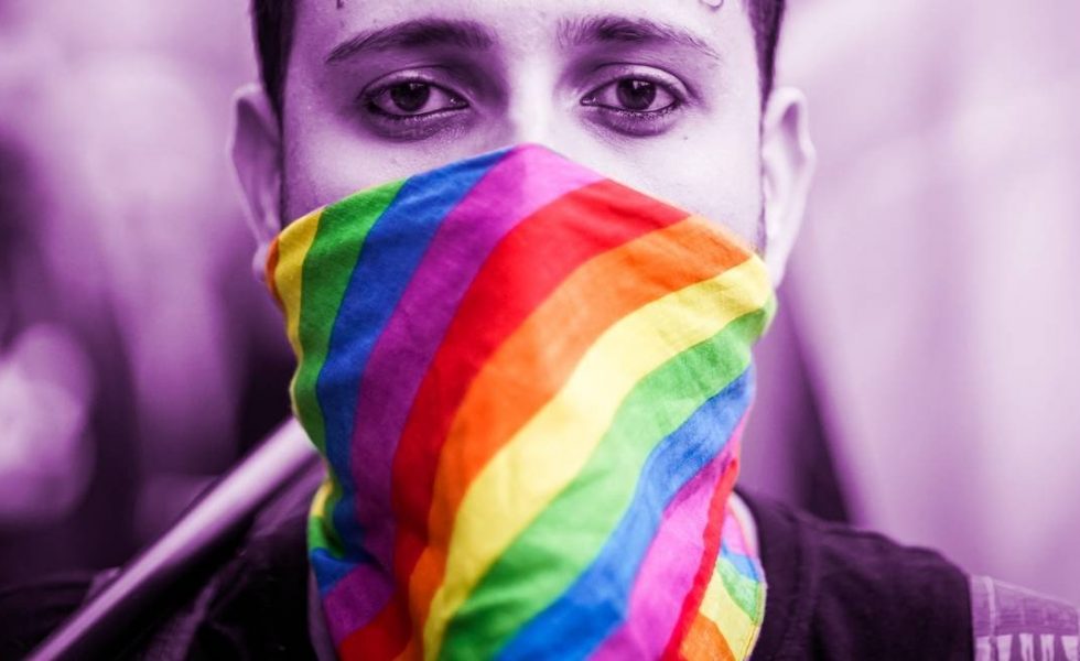 Foto de um homem utilizando uma máscara com as cores do arco-íris.