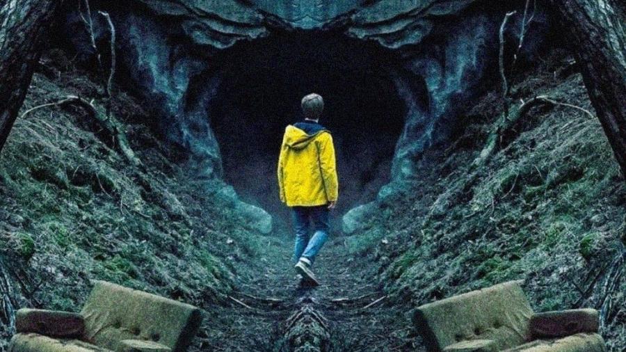 Imagem de um dos personagens principais de frente para o buraco onde tudo começa. Ele está no meio de uma floresta e veste calça jeans e jaqueta amarela.