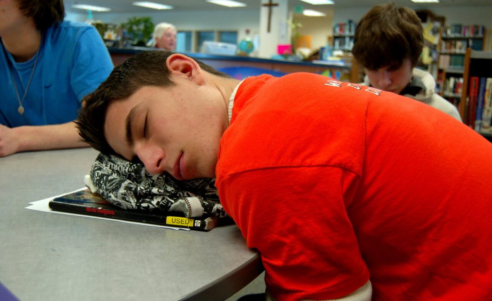 Foto de um adolescente dormindo em cima de um livro.