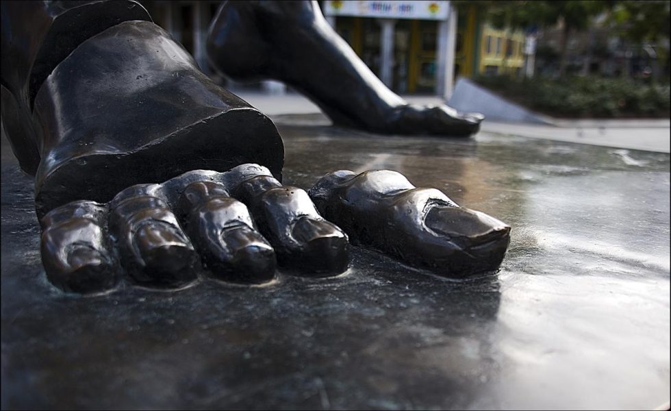Imagem do pé de uma escultura chamada Dolmen de Dal, de Salvador Dalí, localizada em Madri, Espanha. A imagem mostra o pé em foco com os dedos separados do resto do corpo, tudo na cor preta.