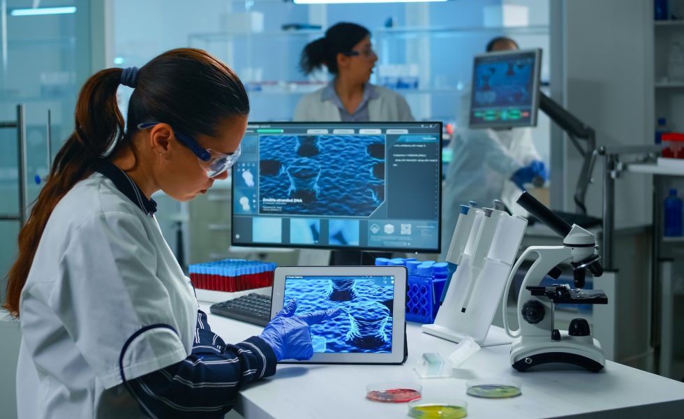 lab technician doctor analyzing virus evolution looking digital tablet team scientists conducting vaccine development using high tech researching treatment against covid19 pandemic 980x600 - (Português do Brasil) Como a IA ajuda a descobrir novos remédios e materiais? (V.7, N.12, P.2, 2024)